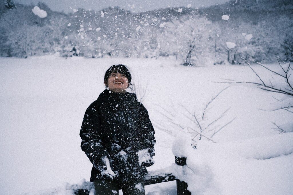 雪が舞う中で笑顔を見せる女性